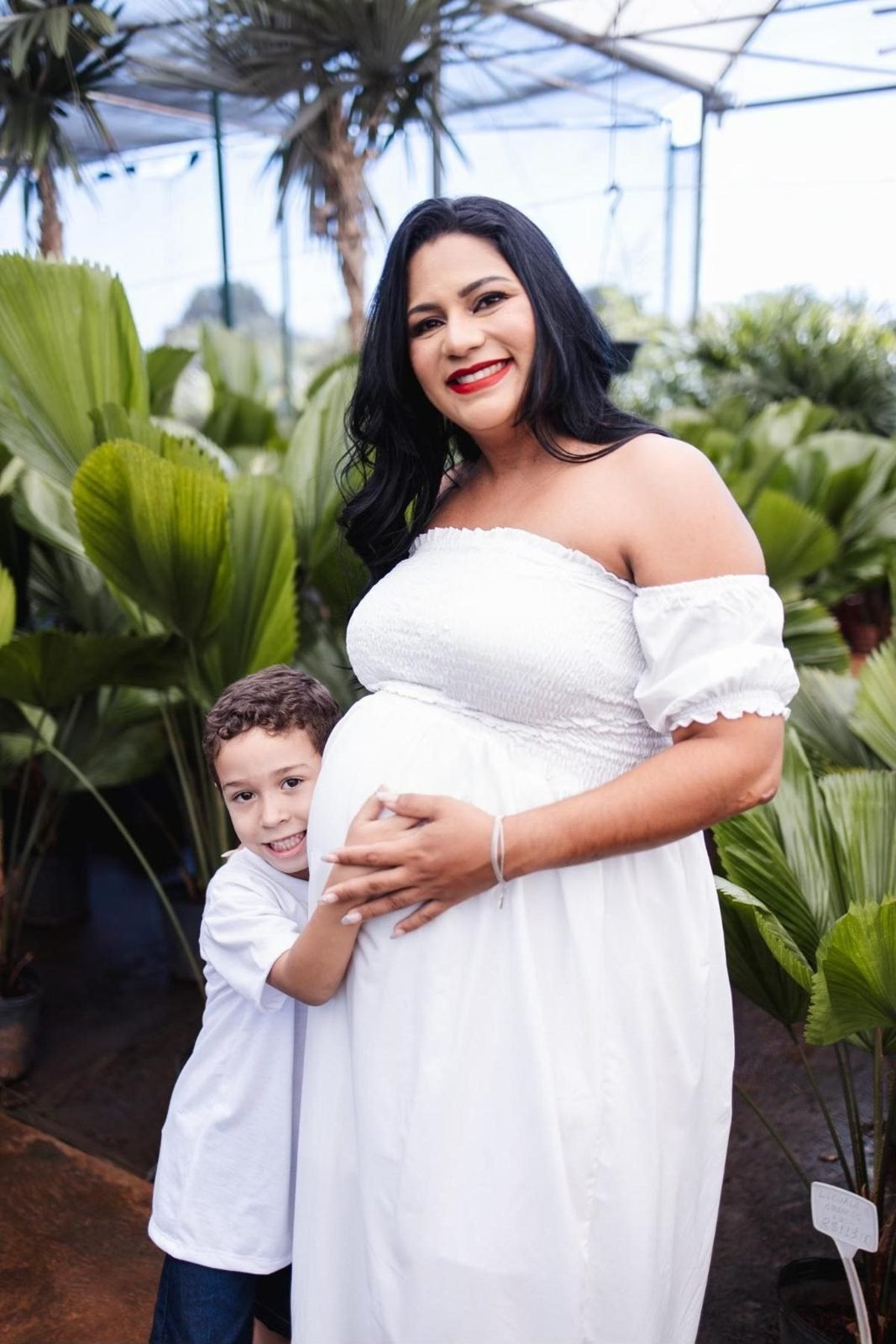 Gestante sorridente abraçada pelo filho